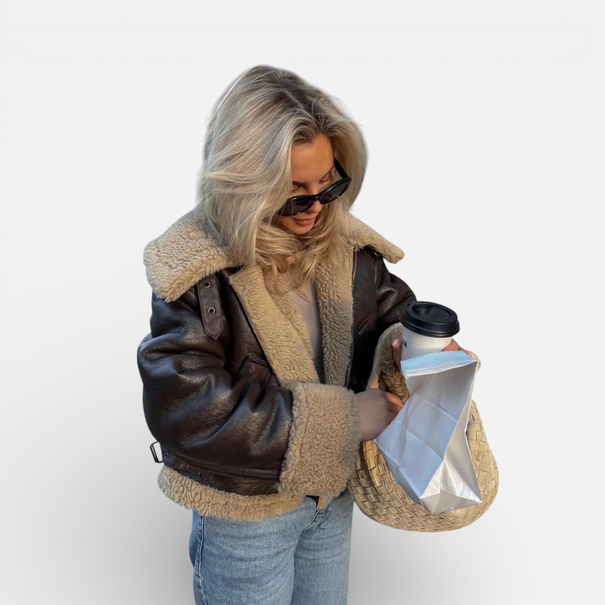 Person wearing a brown shearling jacket holding a coffee cup and a reusable coffee filter.